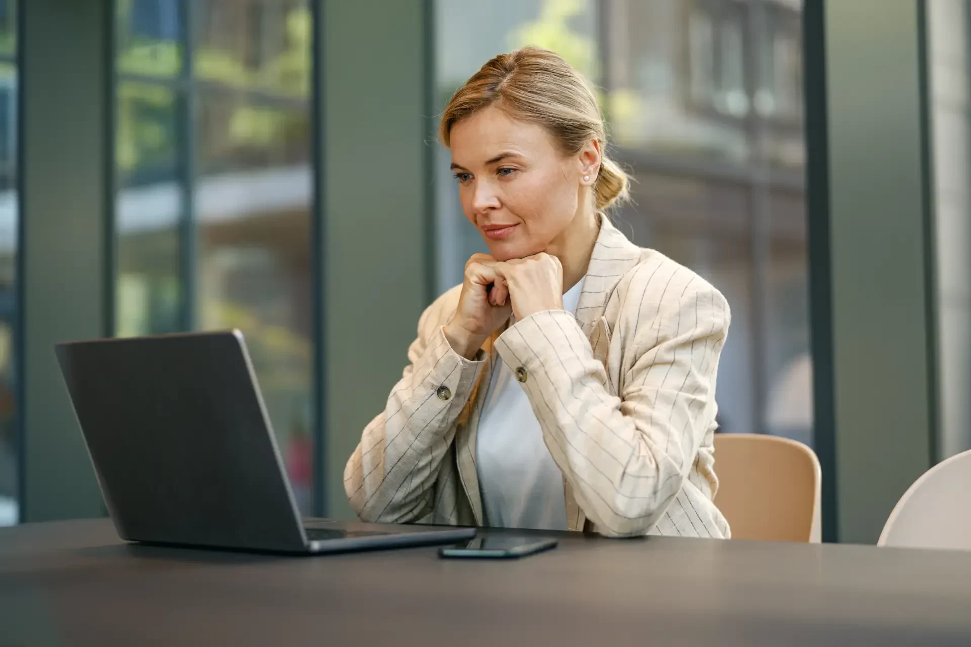 focused-mature-woman-sales-manager-working-laptop-modern-coworking-background